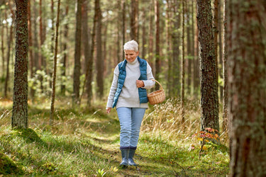 A woman carrying a basket in the woods looking for mushrooms