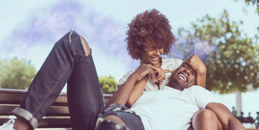 A couple laying on a bench laughing together