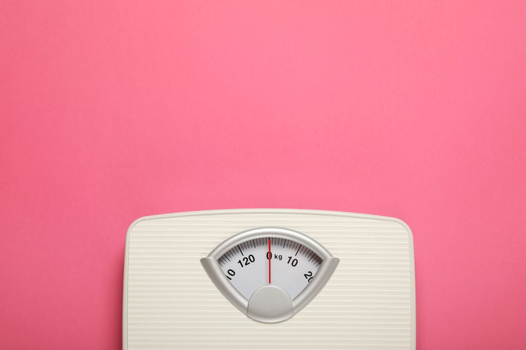 A weighing scale against a pink background
