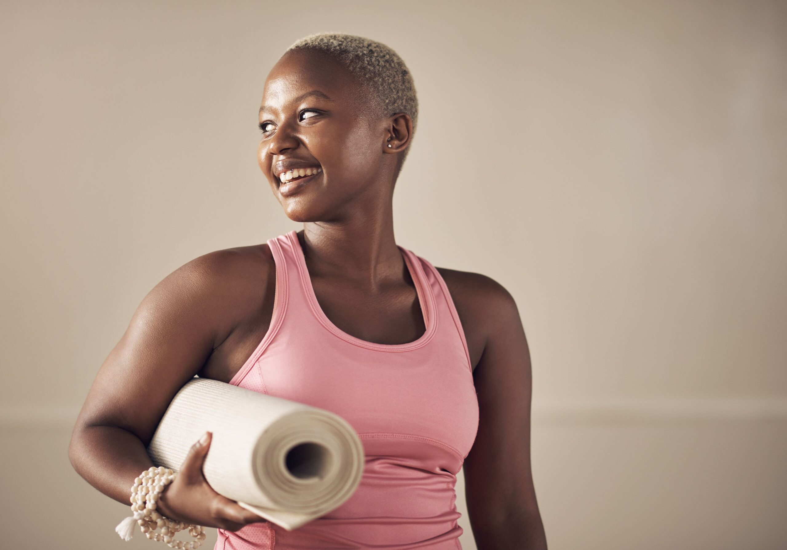 Woman smiling and holding a yoga mat