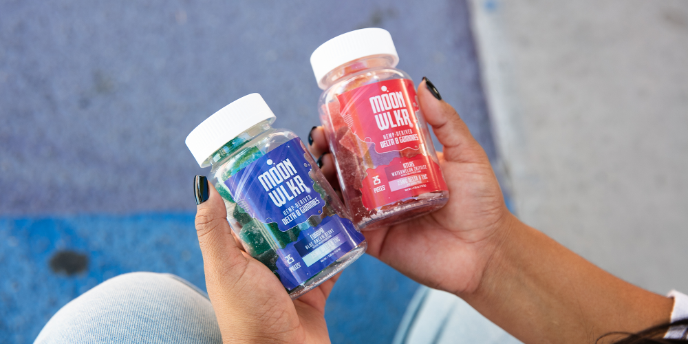 Hands holding out two bottles of Delta 8 gummies
