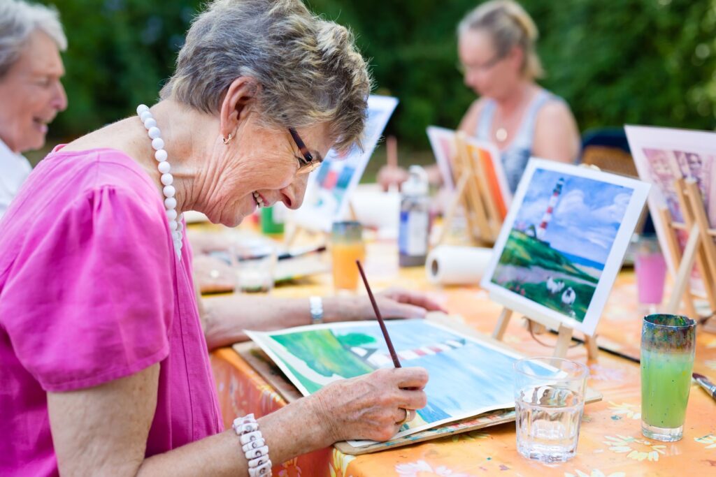 Woman painting outside at a table with friends
