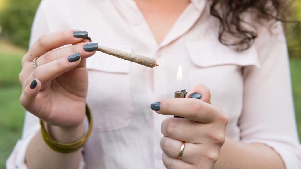 Woman holding a joint in one hand and a lighter in the other preparing to light the joint