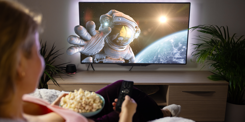 Woman watching TV with an astronaut reaching out of the frame