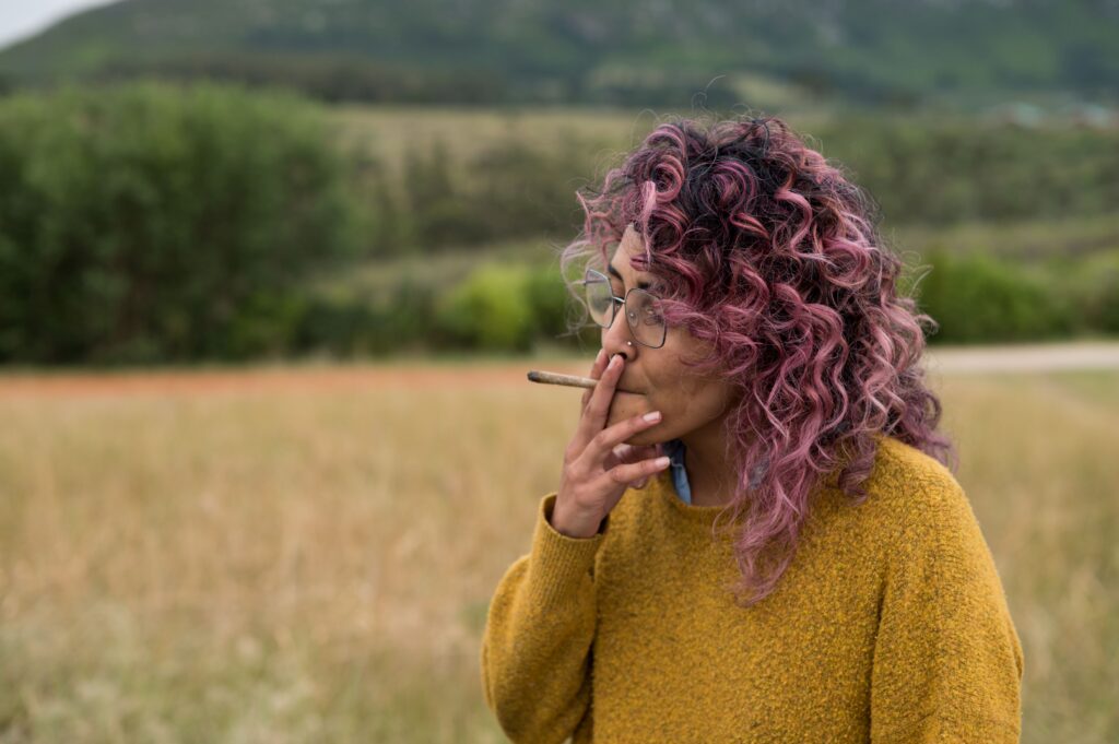 Woman smoking a pre-roll out in a grass field