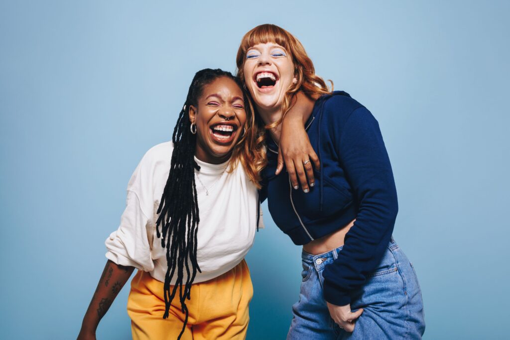 Two women leaning on each other and laughing together