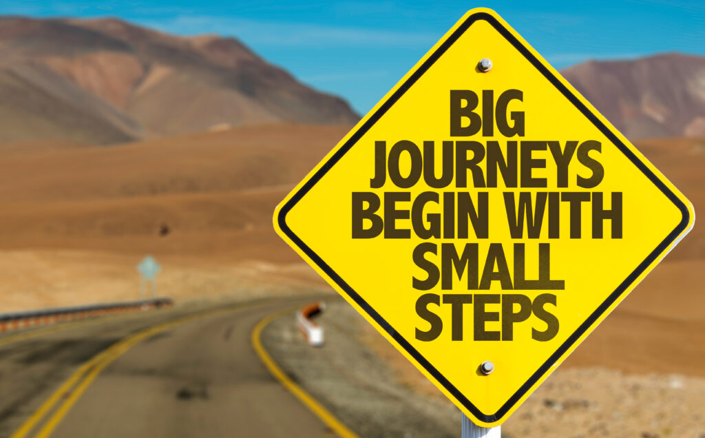 A road sign that states "big journeys begin with small steps"