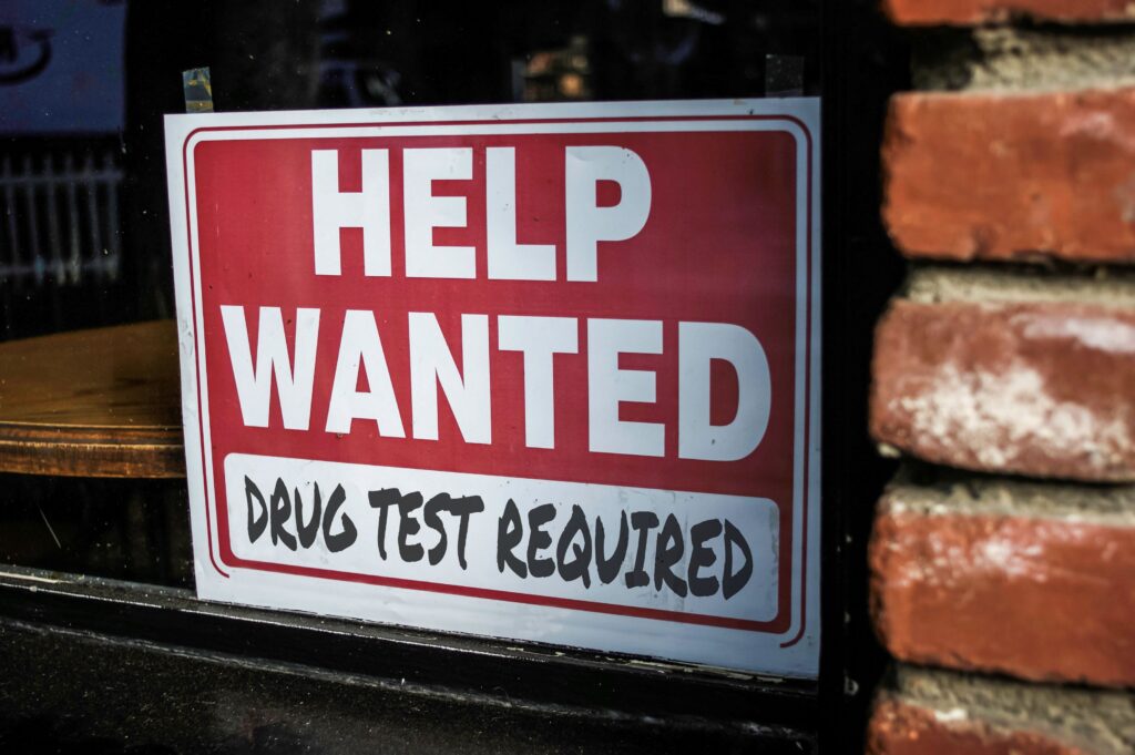 Help Wanted Sign in a shop window that states drug test required