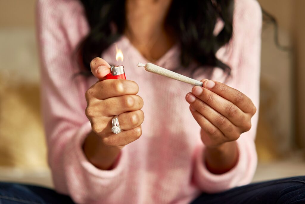 A woman's hands holding a lighter in one and a joint in the other about to spark it