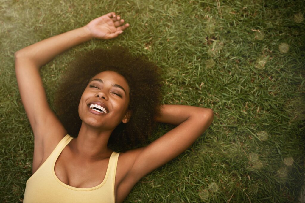 Woman laying in the grass while smiling in euphoria