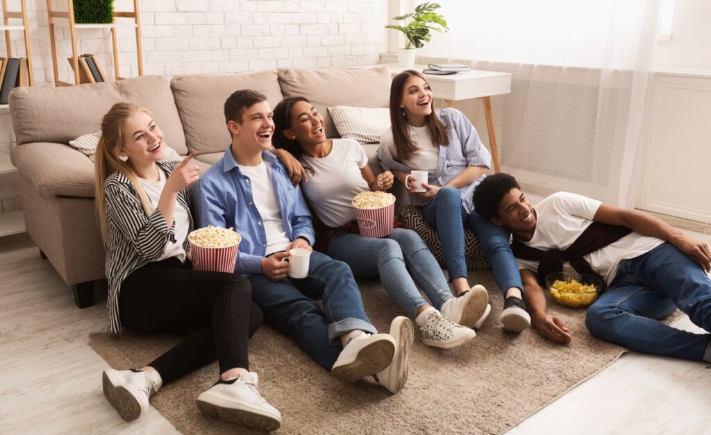 A group of friends eating popcorn and watching TV together